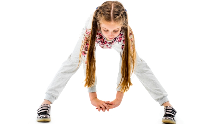 Little girl do forward bend exercise in grey sportwear.