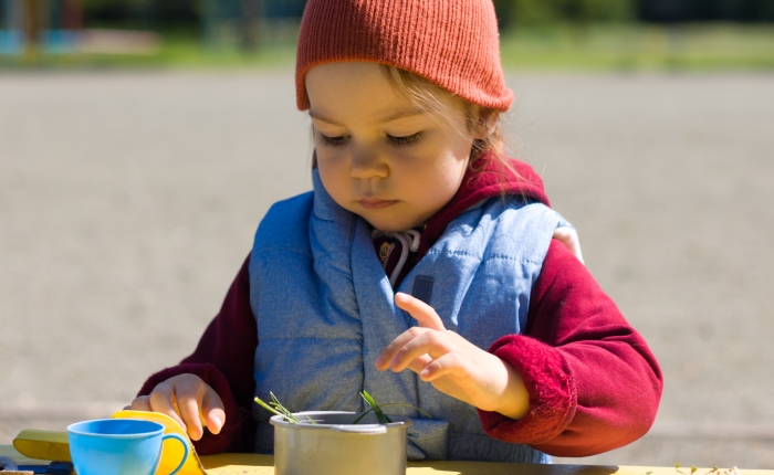 Little girl play with set of children's toy colorful dishes.