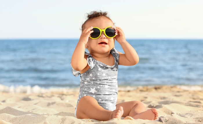 Little girl with sunglasses on beach at resort.