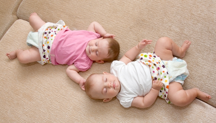 Little sisters twins baby girls sleeping on the sofa.