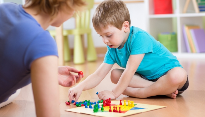 Mother and her child son playing in board game.