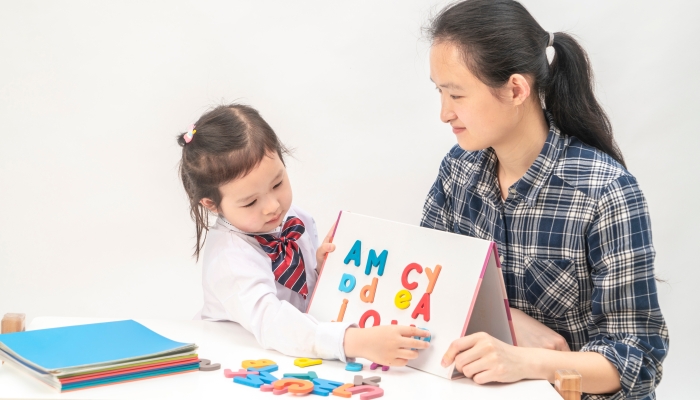 Mother and little girl are learning English letters.