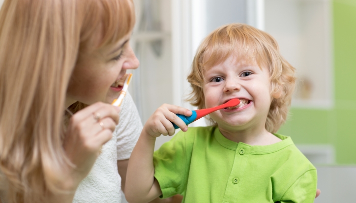 Mother teaches her child son how to brush teeth.