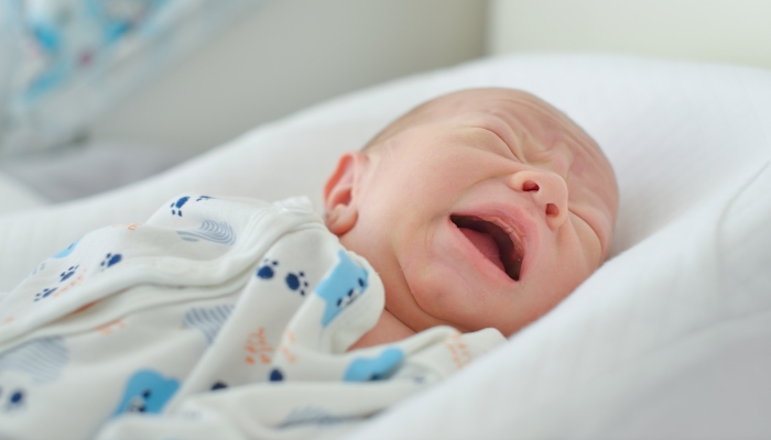 Newborn baby crying and laying in the crib.