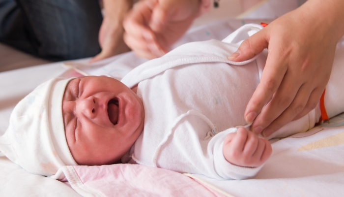 Newborn baby crying on the bed.