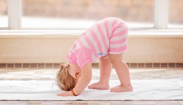 Portrait of cute adorable white Caucasian baby girl doing physical fitness exercises yoga.