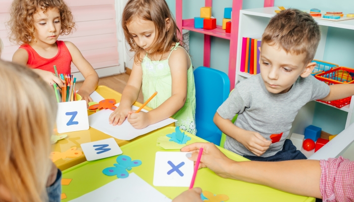 Preschool children learn english alphabet using cards.