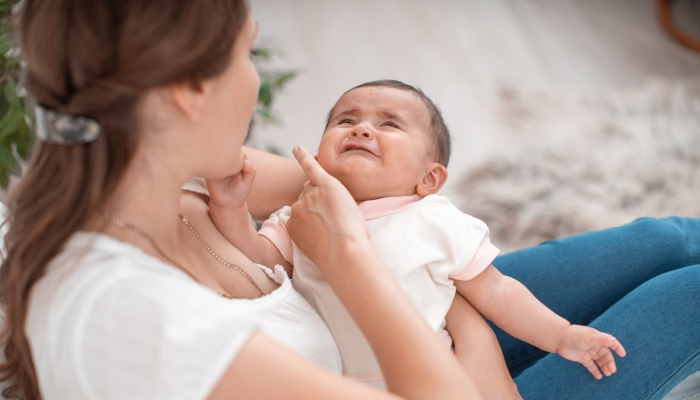 The baby is crying in his mother's arms.