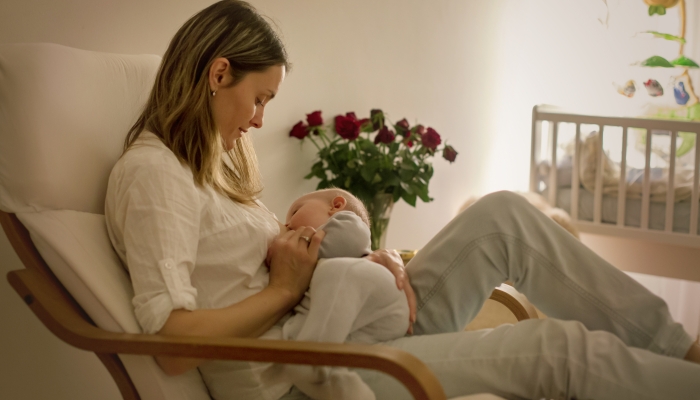 Young beautiful mother, breastfeeding her newborn.