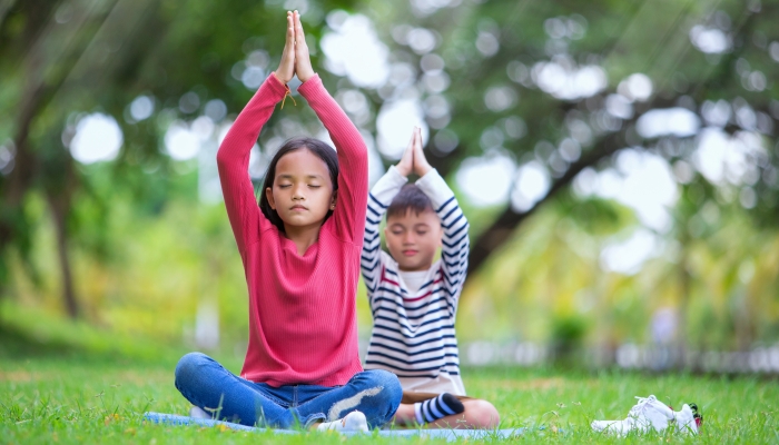 asian kids doing yoga pose in the park outdoor.