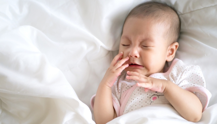 Adorable little Asian baby infant girl cry on white bed.