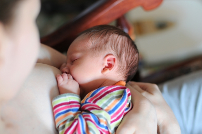the newborn sleeps on the mother's breast while breastfeeding.