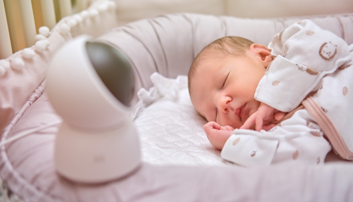 A home surveillance camera looks at the crib with a sleeping newborn baby.