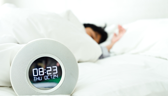 Alarm clock and little boy sleeping in the bedroom.