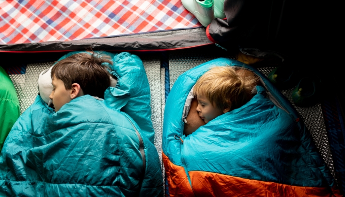 Children, sibilngs, sleeping in sleeping bags in a tent in Norway.