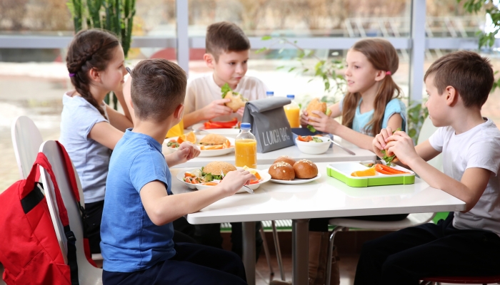 Children sitting at cafeteria table while eating lunch.