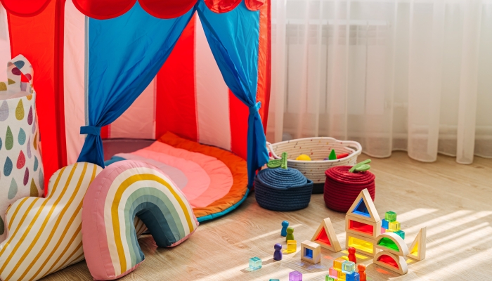 Children's room with a play tent, pillows and toys in baskets.