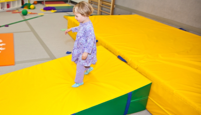 Cute little European toddler girl having fun at indoor playground.