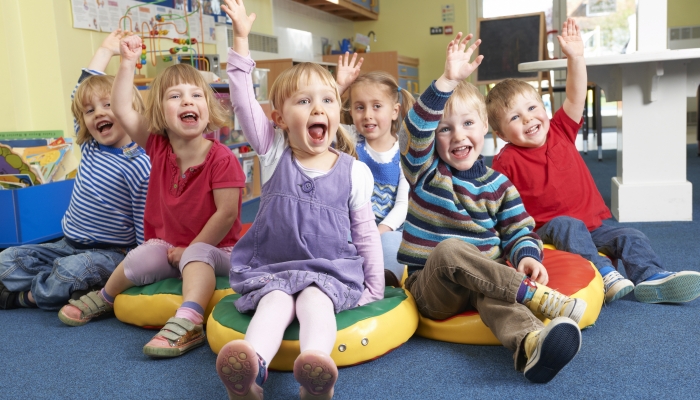 Group Of Pre School Children Answering Question In Classroom.