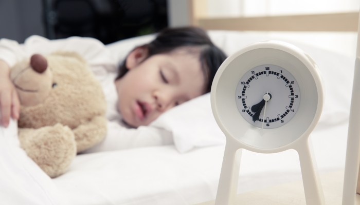 Happy asian child girl and alarm clock wake up in the morning.