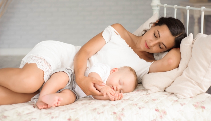 Little boy lies near his mom resting on the bed.