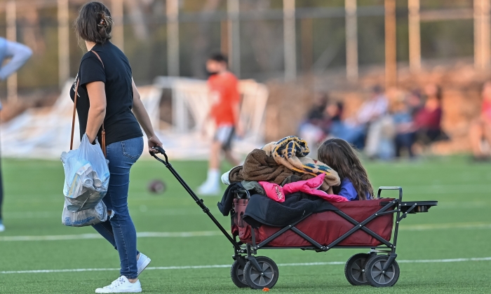 Little girl being pulled in a wagon at a sporting event.