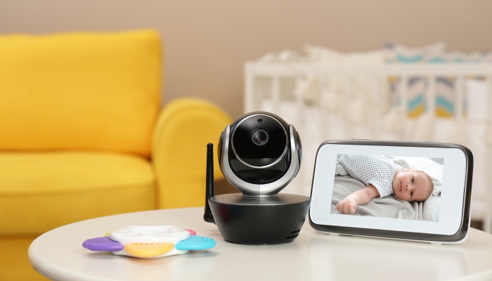 Modern security CCTV camera and monitor with baby's image on table.