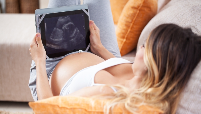 Pregnant woman looking her baby on ultrasound image.