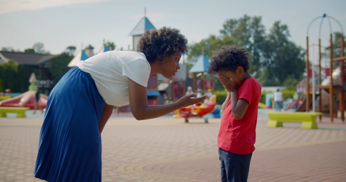 Side view of african strict mother talking to naughty son in park.