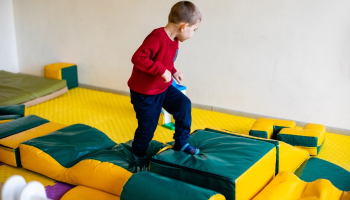 The boy is climbing on a soft blocks.