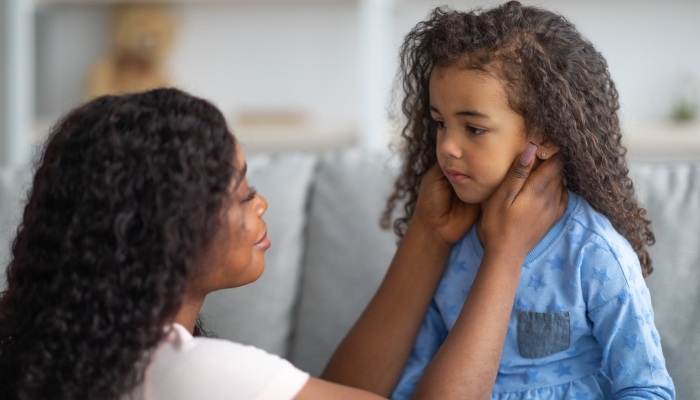 Young black mother comforting her sad offended daughter after quarrel at home.