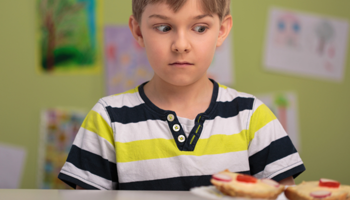 A boy tentatively looking at his lunch.