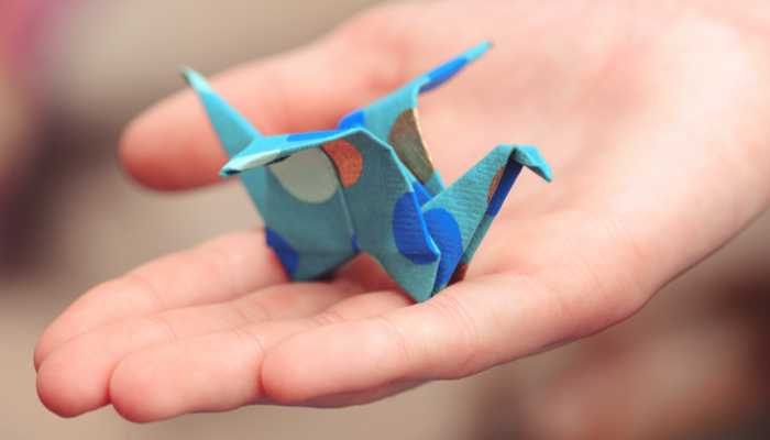 A child holding a folded crane in their hand.