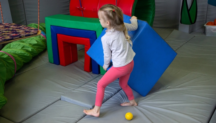 Girl with a psychologist plays in colored soft cubes.