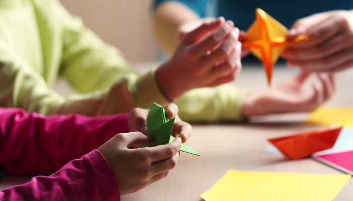 A group of kids folding origami together.