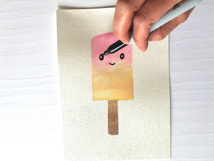 Use a marker to draw a face on your watercolor popsicle painting.