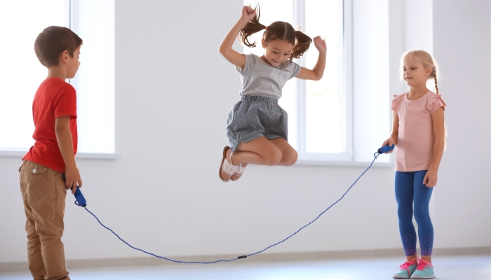 Adorable children skipping rope indoors.