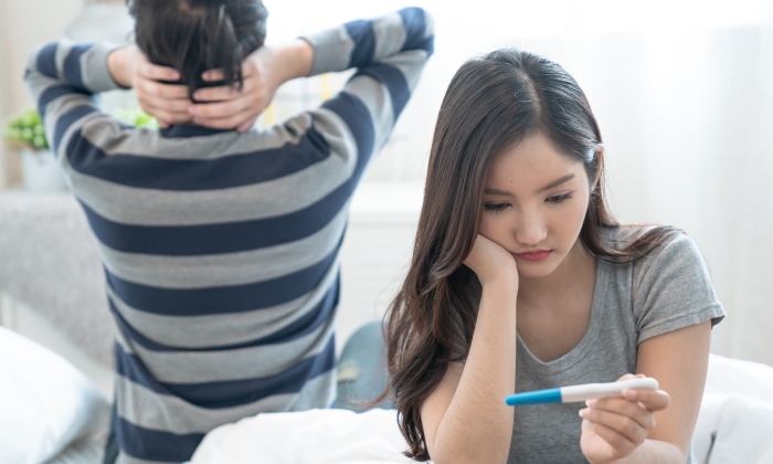 Asian couples are disappointed when they learn the results of a pregnancy test.
