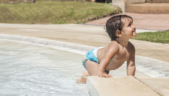 Baby girl crawling in the pool shore.