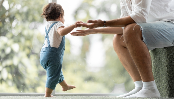 Baby learning to walk with father.