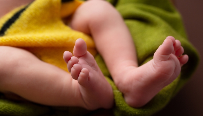 Cute baby shaking feet while lying in bed.