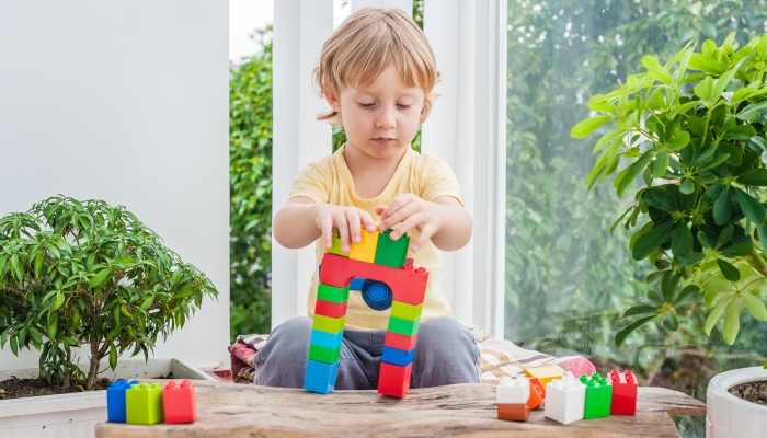 Cute little kid boy with playing with lots of colorful plastic blocks indoor.