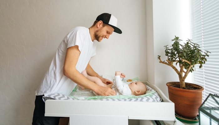 Father change diaper to baby boy on a baby changing table.
