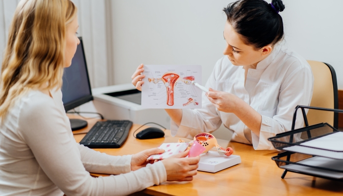 Female doctor showing female patient picture of uterus.