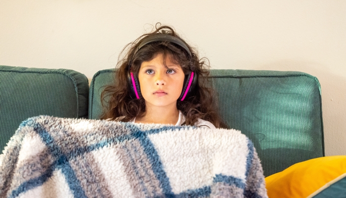 Girl with sensory processing disorder with noise canceling headphones.
