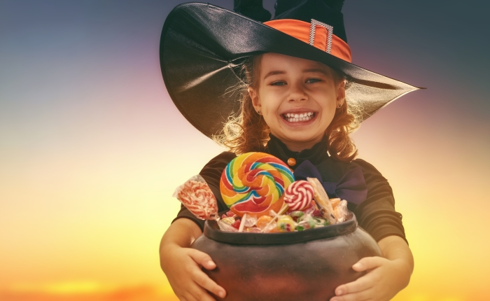 Happy Halloween! Cute little witch with candy.