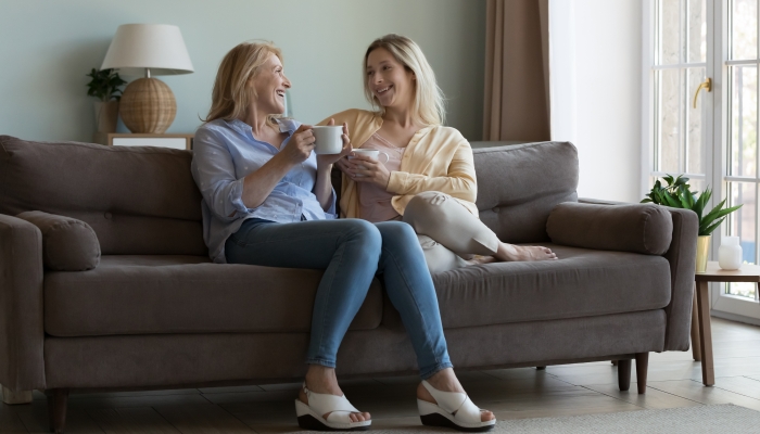 Happy middle aged moms chatting over cup of coffee.