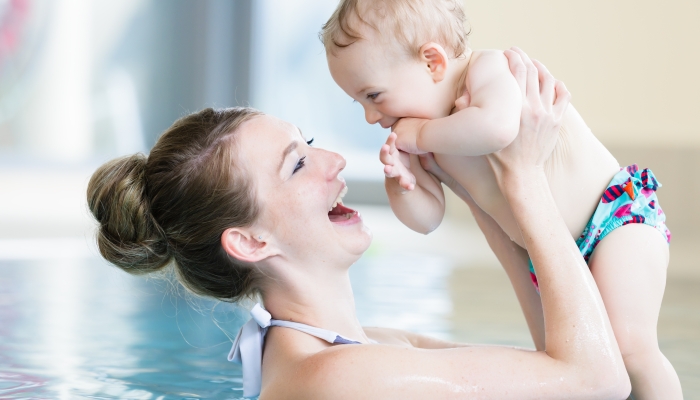 Happy mother and her newborn child at infant swimming class.