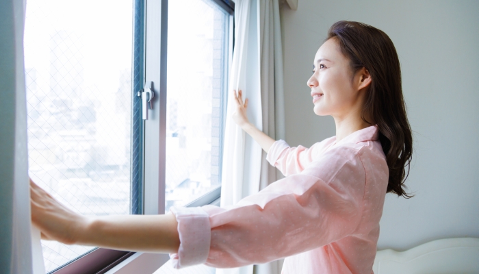 Japanese woman in pajamas standing by the window.