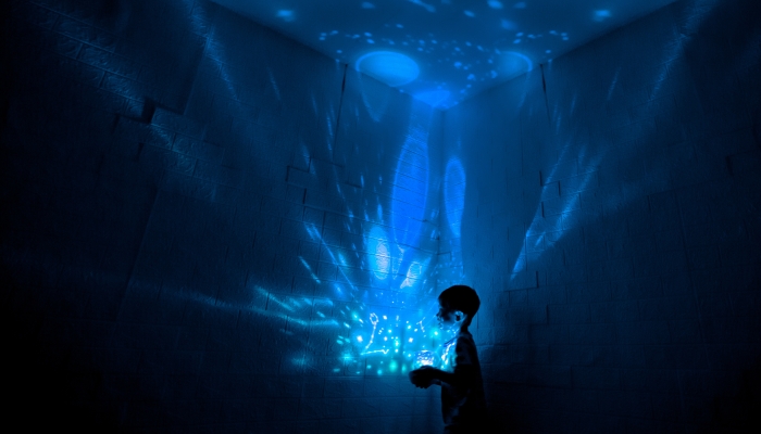 Little boyl in his room with night light projecting stars on room ceiling.